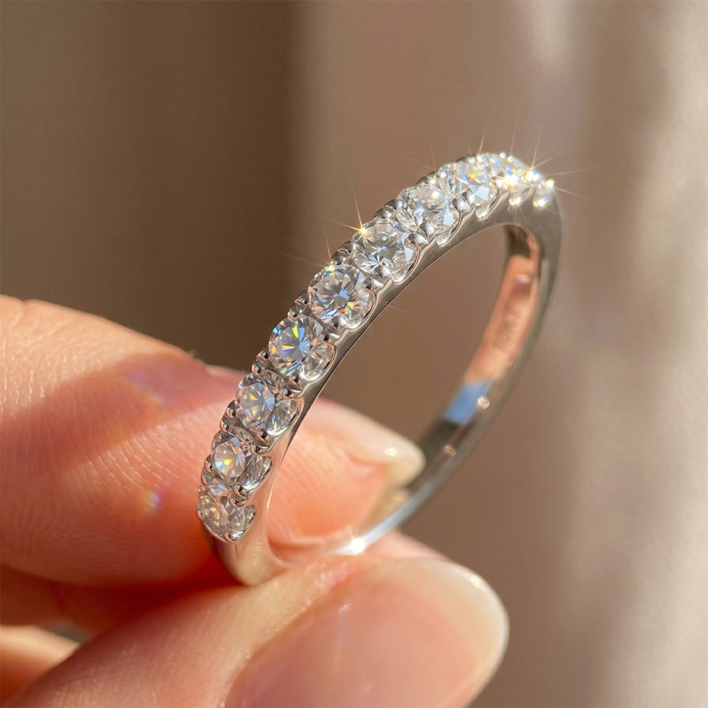 Hand holding 18kt white gold round brilliant lab diamond half eternity wedding ring in soft sunlight