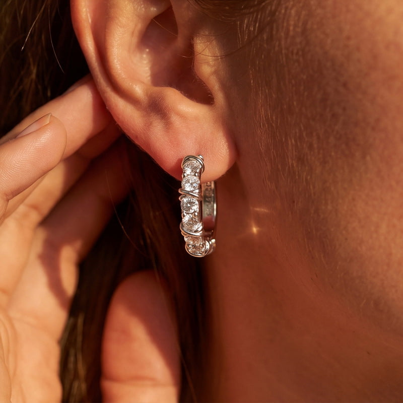 Model wearing 1CT lab grown diamond X cross cable wire huggie hoop earrings.