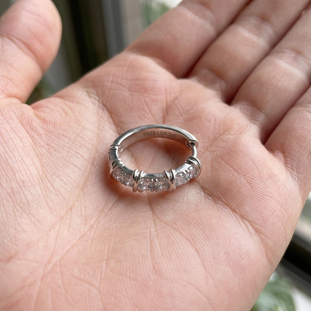 Hand holding lab grown diamond X cross cable huggie hoop showing metal engraving and size.