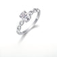 Silver 1ct oval moissanite ring with hollow chain link band standing on display.