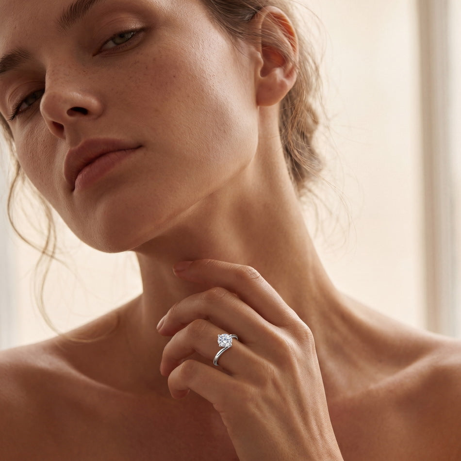 Model wearing 1ct round diamond bypass solitaire engagement ring on finger.