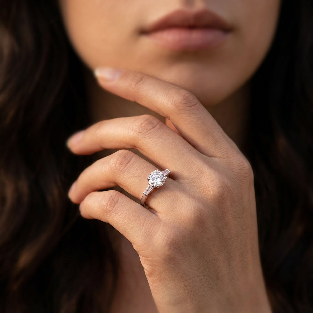 Close-up view of a model wearing 1CT round moissanite three-stone ring with tapered baguette accents.