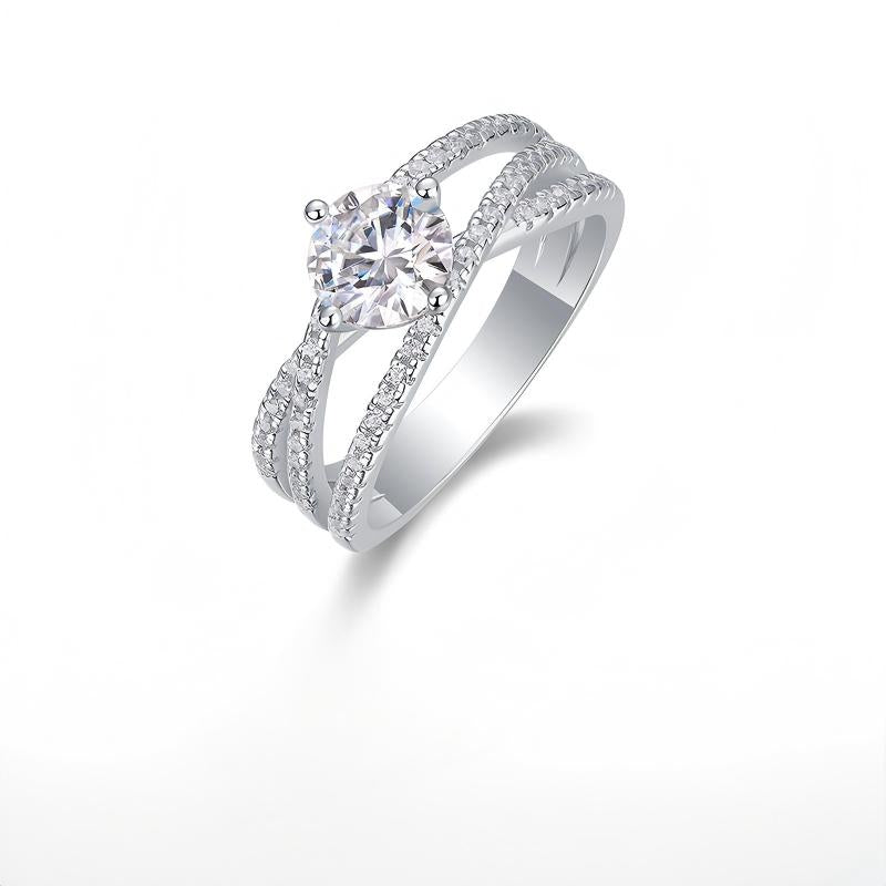 Silver 1ct round moissanite engagement ring with crossover pave band standing on display.