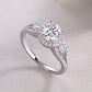 Silver 1CT round moissanite halo ring with baguette side accents resting on a soft background.