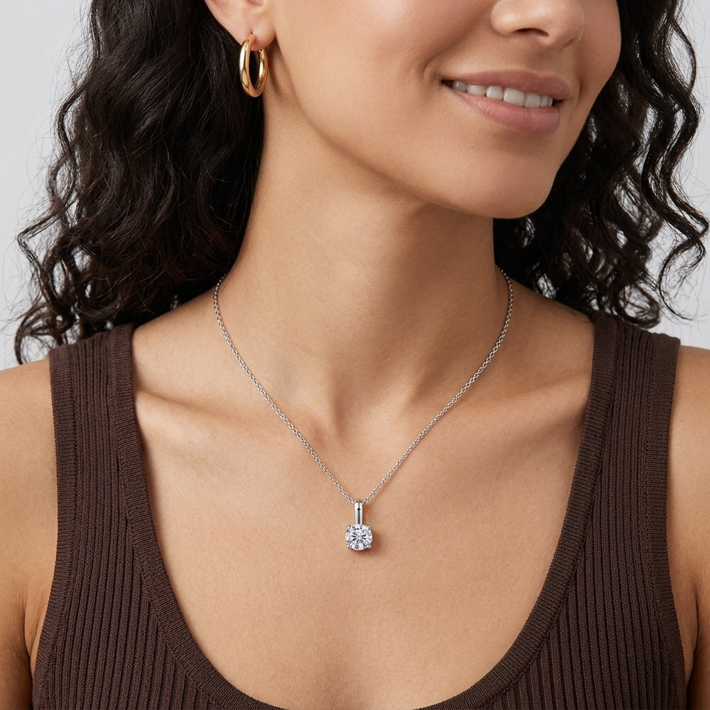 Model wearing 1ct round brilliant solitaire diamond pendant necklace on collarbone.