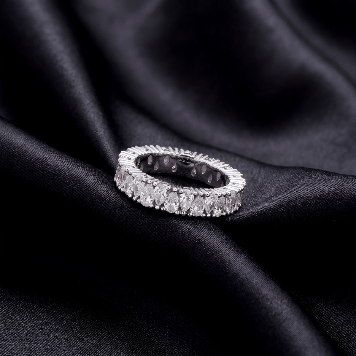 2.78 ctw pear cut lab grown diamond eternity wedding band resting flat on dark black silk