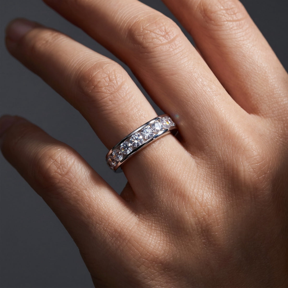 Close up of woman wearing 2 ctw channel set round lab grown diamond eternity ring on hand