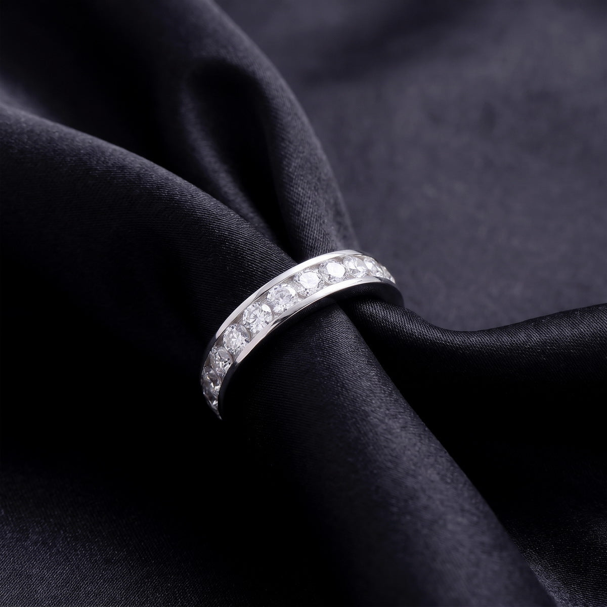 Angled side view showing channel setting profile of 2 ctw lab grown diamond eternity ring on black silk