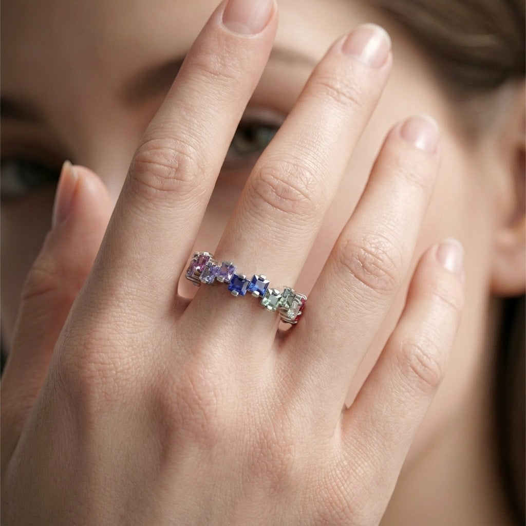 Model wearing gold 2.5mm princess cut rainbow gradient gemstone eternity band ring on hand