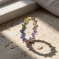Silver 2.5mm princess cut rainbow gradient gemstone eternity band ring standing on travertine stone