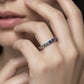 Model wearing gold 2.5mm round rainbow gradient gemstone eternity band ring on finger