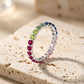 Silver 2.5mm round rainbow gradient gemstone eternity band ring standing on beige travertine stone