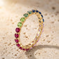 Gold 2.5mm round rainbow gradient gemstone eternity band ring standing on travertine stone surface   
