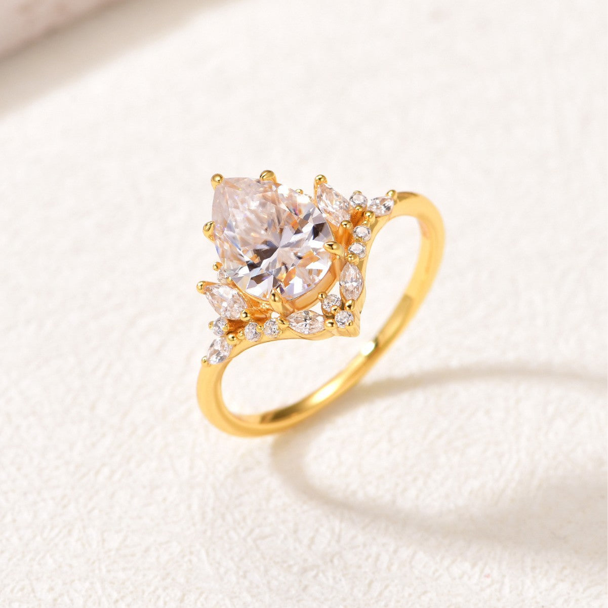 Yellow gold 2CT pear moissanite ring on soft romantic background. Alt: “2CT Water Drop Moissanite Engagement Ring – 18K Yellow Gold.”