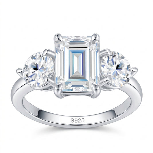 2ct emerald cut moissanite three-stone ring with round side accents on white background.