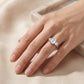 Model showing 2ct emerald cut moissanite three-stone ring in soft ambient lighting.