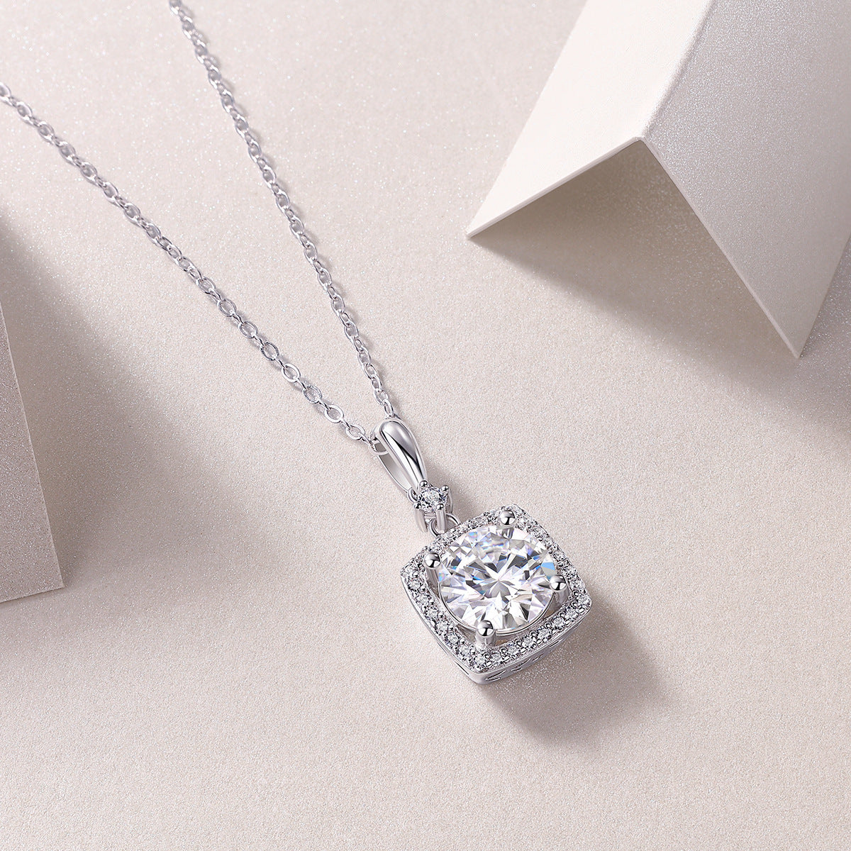 Close-up view of 2ct round moissanite square cushion halo pendant on chain.