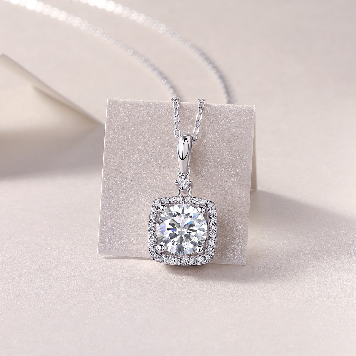 2ct round moissanite cushion halo pendant with accent bail on stone card.
