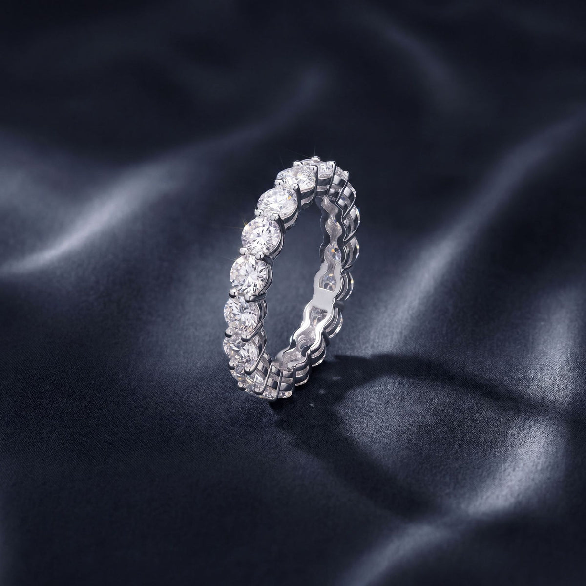 Vertical perspective view of 3.54ct round cut lab grown diamond full eternity ring on black silk.