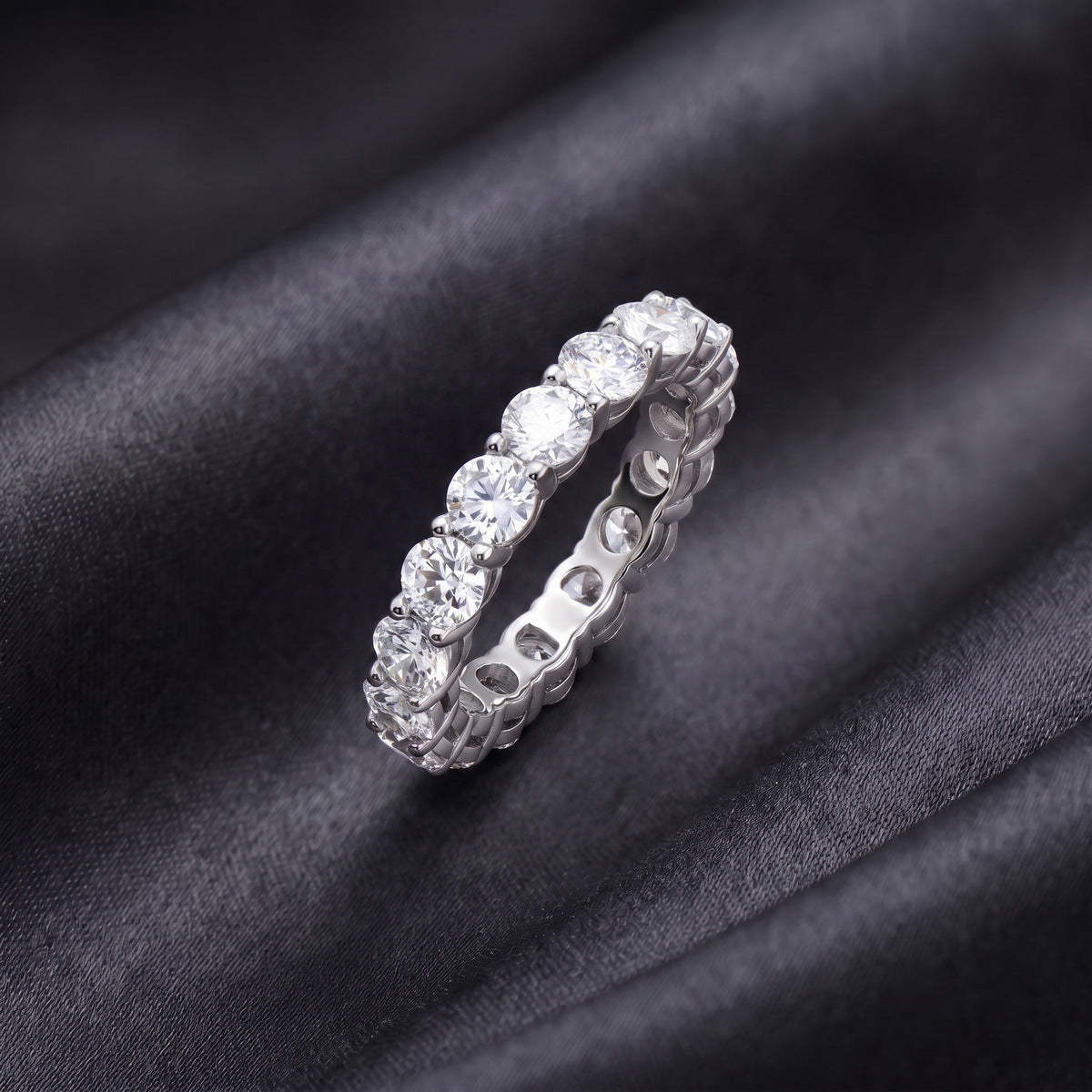 Side profile view showing shared prong setting of 3.84 ctw lab grown diamond eternity ring on black silk