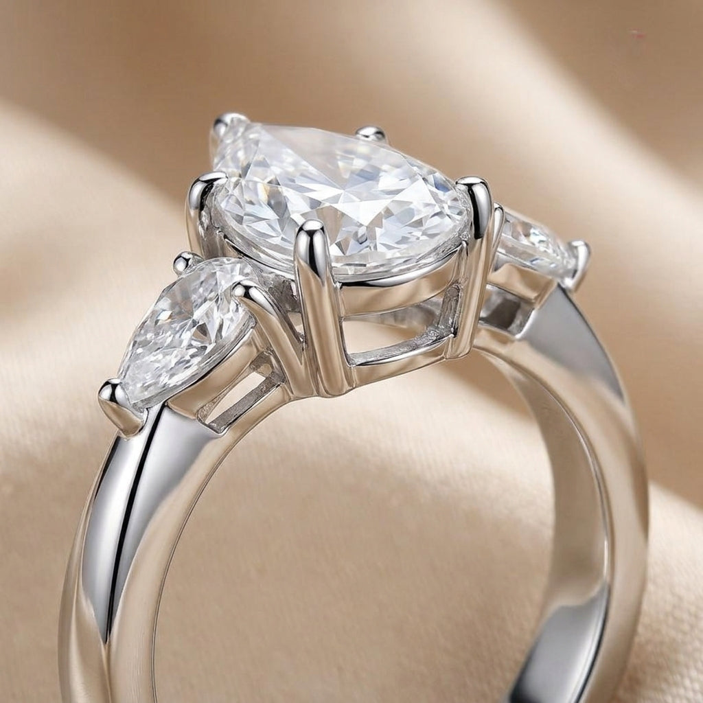 Side profile view showing prong basket setting and pear side accents on silver moissanite ring.