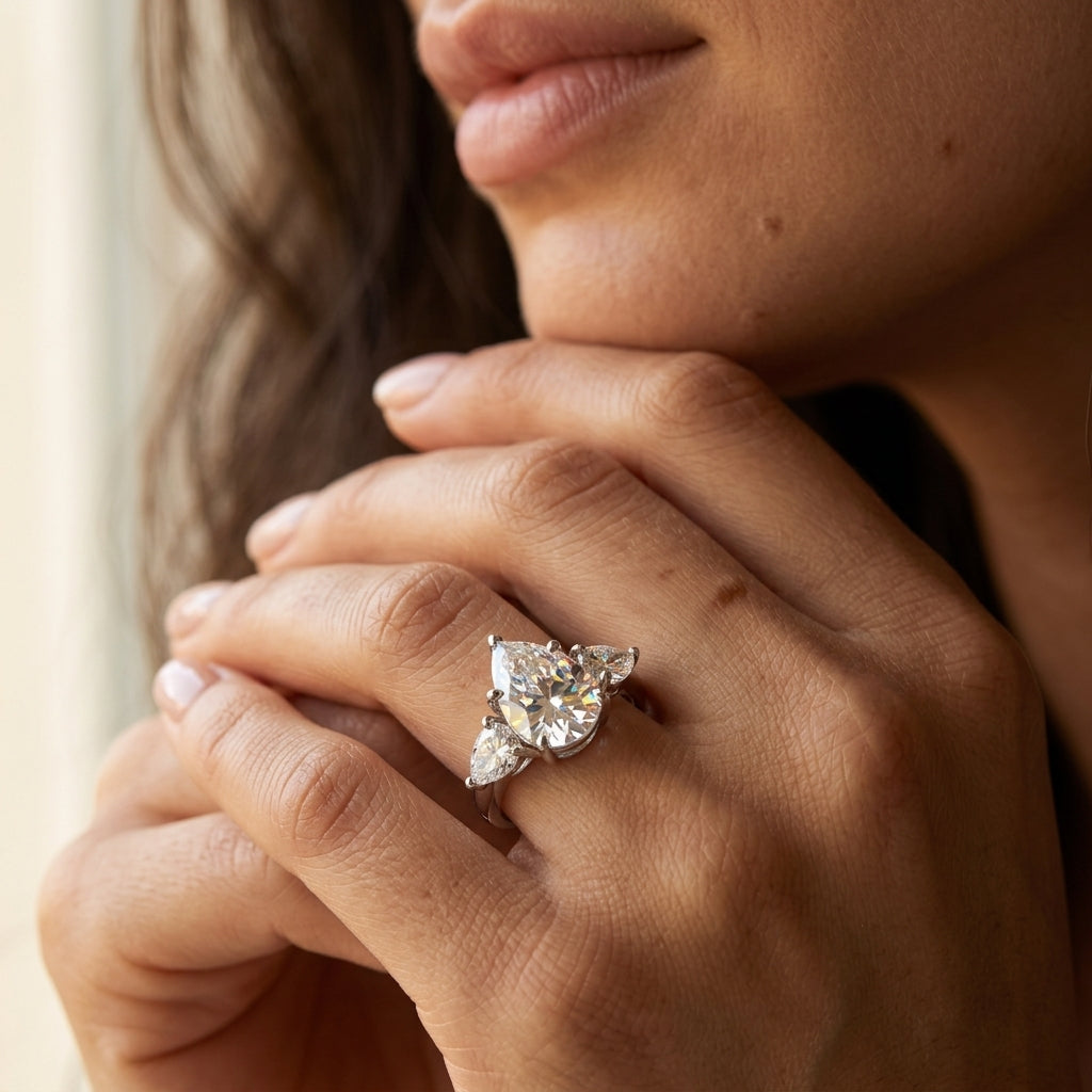 Close-up view of a model wearing a 3CT pear cut moissanite three-stone ring.