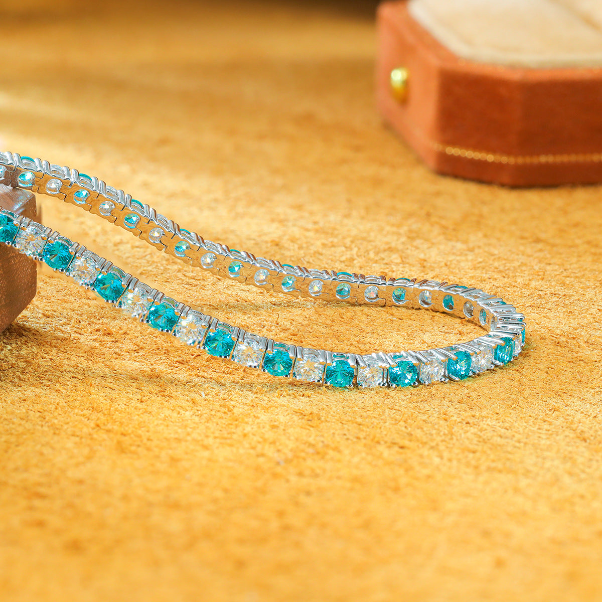 Hand held close up view of 3.0mm lab grown paraiba tourmaline and moissanite tennis bracelet