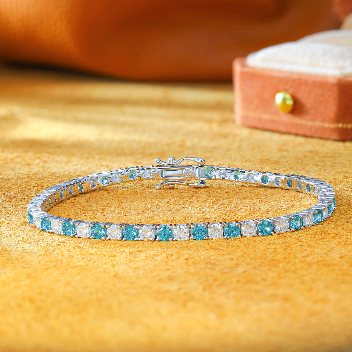 3.0mm lab grown paraiba tourmaline and moissanite tennis bracelet laid out on yellow velvet backdrop