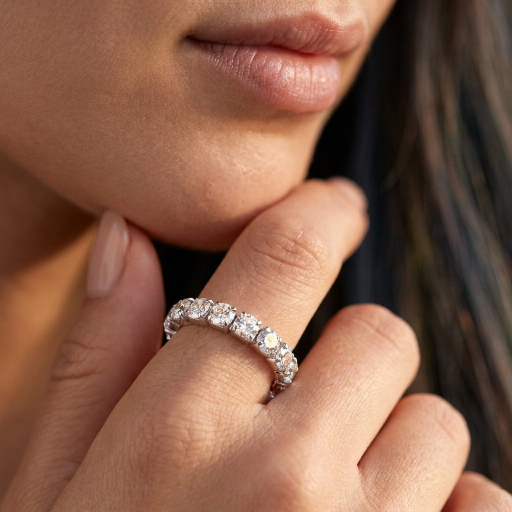 Model wearing 3mm round moissanite shared prong eternity wedding band.