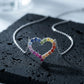 Silver 3mm round rainbow gradient open heart pendant necklace resting on textured black volcanic stone