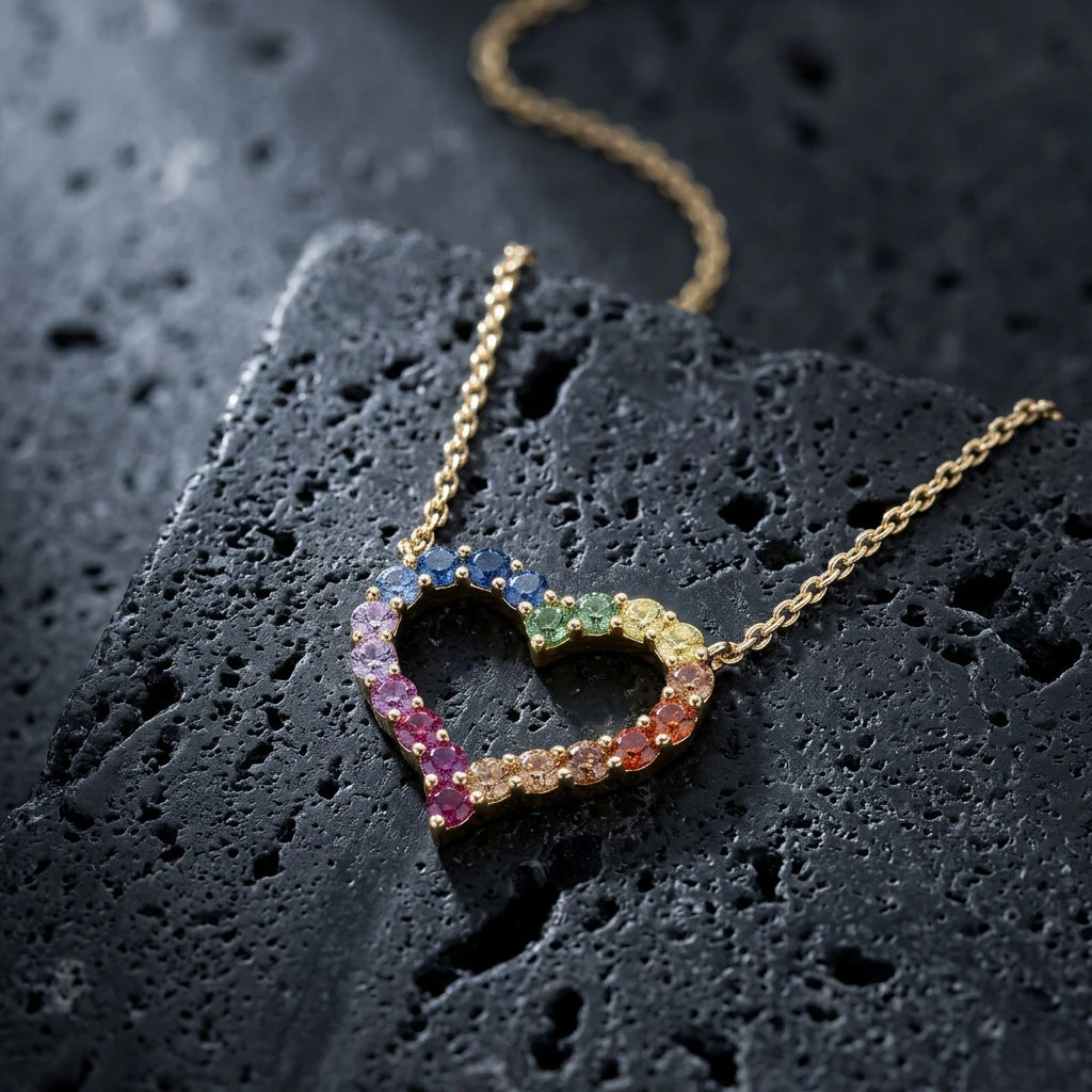 Gold 3mm round rainbow gradient open heart pendant necklace displayed on dark textured stone surface