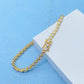 A gold tennis bracelet with clear round-cut stones, displayed on a white textured block against a light blue background.