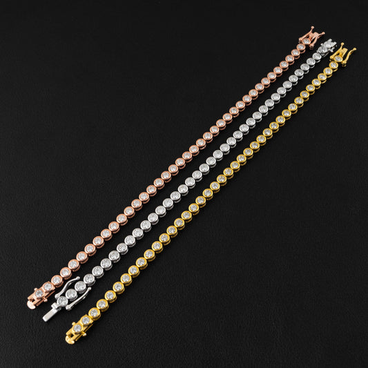 Three tennis-style bracelets with round stones in rose gold, silver, and yellow gold, arranged diagonally on a black textured background.