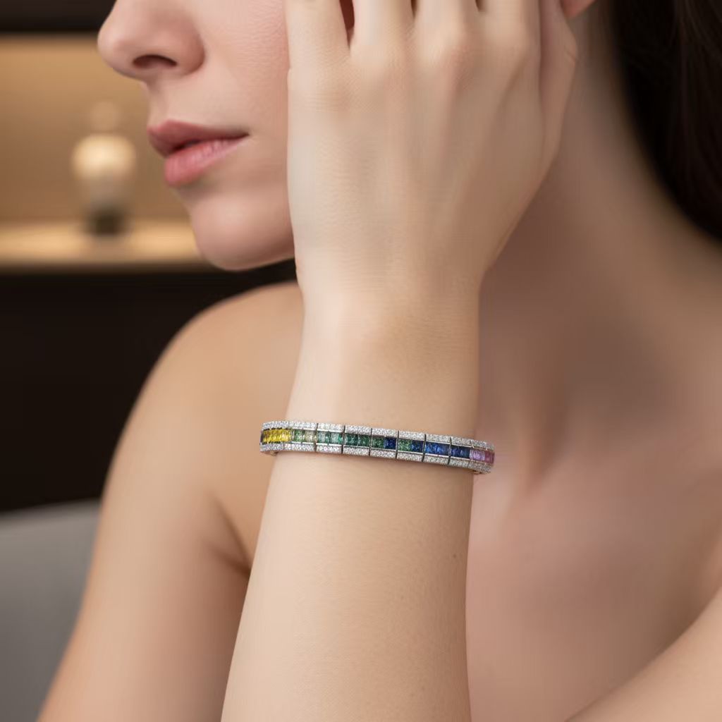 Model wearing gold 3x3mm princess cut rainbow channel-set tennis bracelet on wrist