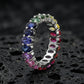 Silver 3x5mm oval cut rainbow eternity band ring on textured black volcanic stone surface