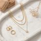 Top-down, necklaces on marble tray, styled with earrings, ring, dried flower, velvet box, warm soft tones, balanced composition, clean e-commerce aesthetic, high resolution.