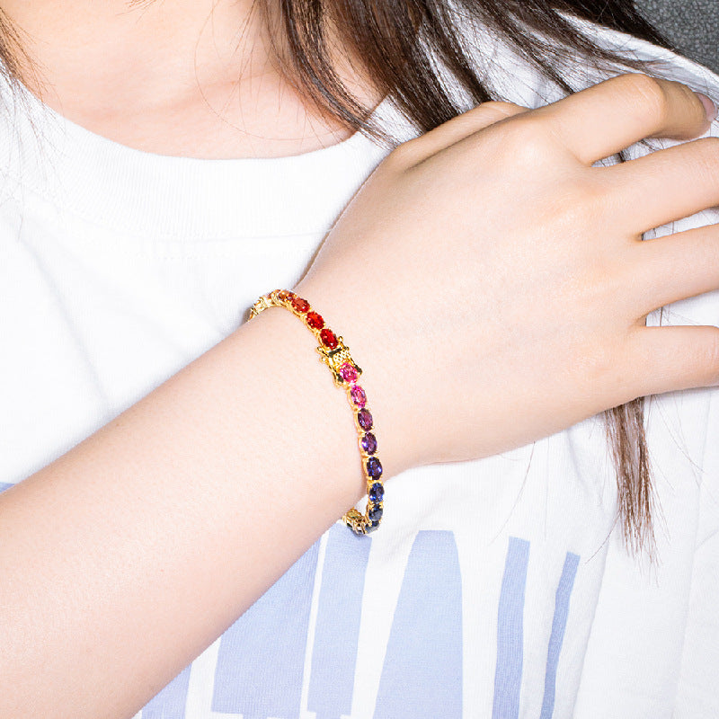Model wearing gold 4x6mm oval cut rainbow gradient moissanite tennis bracelet on wrist