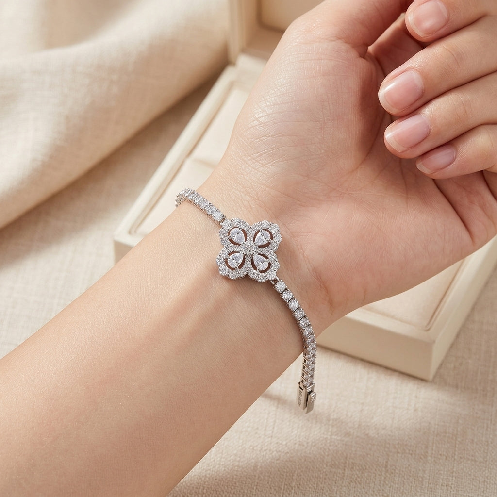Model hand wearing 5.52 CTW diamond quatrefoil flower tennis bracelet near jewelry box.