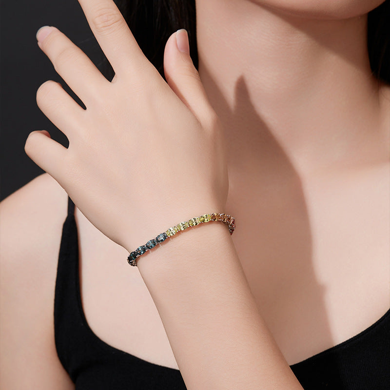 Model wearing gold 5mm oval cut rainbow gradient moissanite classic tennis chain bracelet on wrist