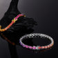 Gold and silver 5mm oval cut rainbow gradient moissanite tennis bracelets displayed on dark stone background