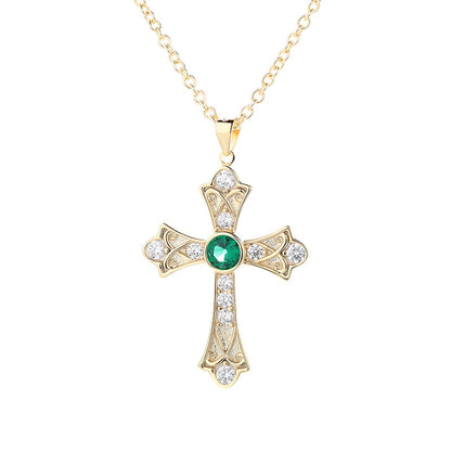 Gold cross pendant with a green gemstone on a white background