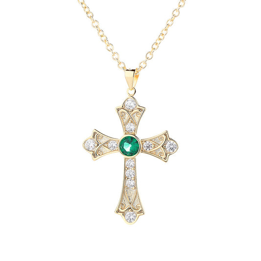 Gold cross pendant with a green gemstone on a white background
