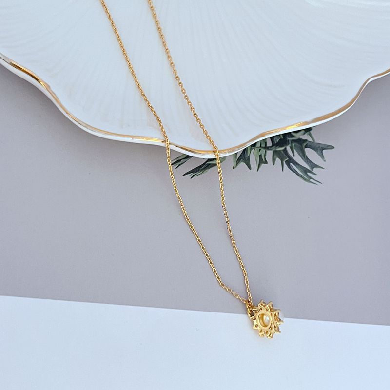 Necklace on a soft, bright background (light blue or creamy white), highlighting the sun pendant's pearl center and crystal halo. Alt: “Kate Spade Sunny Pave & Imitation Pearl Halo Necklace – Radiant Sun Motif Jewelry.”