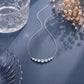 Perspective shot of 7-stone graduated lab diamond curved bar necklace on blue background.