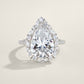 Silver 8CT pear cut moissanite ring with starburst marquise cluster halo standing on a light background.