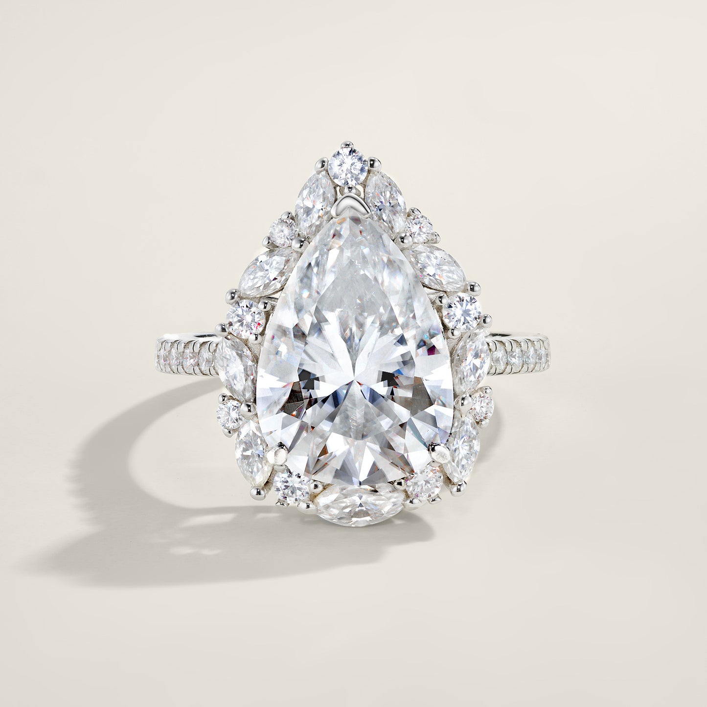 Silver 8CT pear cut moissanite ring with starburst marquise cluster halo standing on a light background.