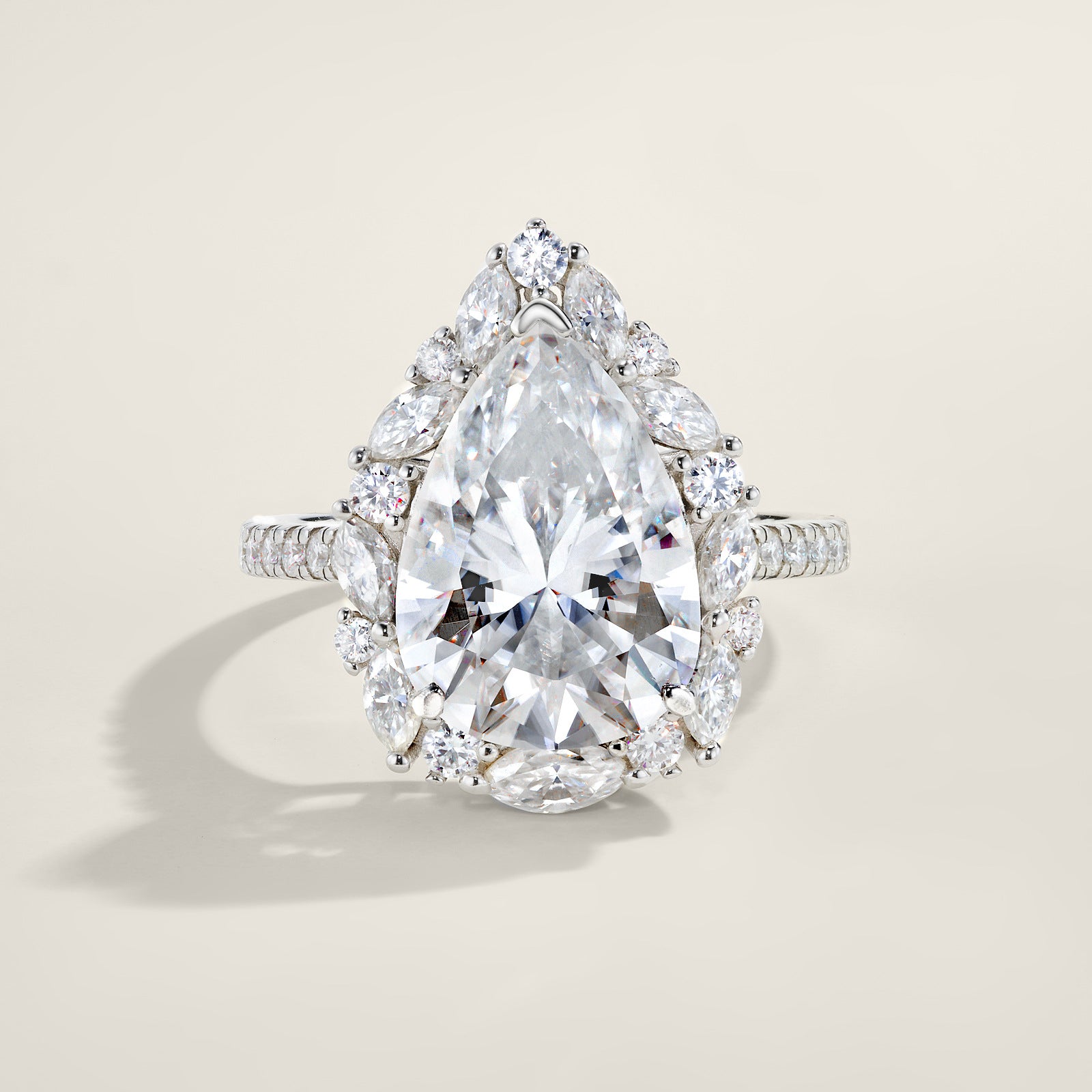 Silver 8CT pear cut moissanite ring with starburst marquise cluster halo standing on a light background.