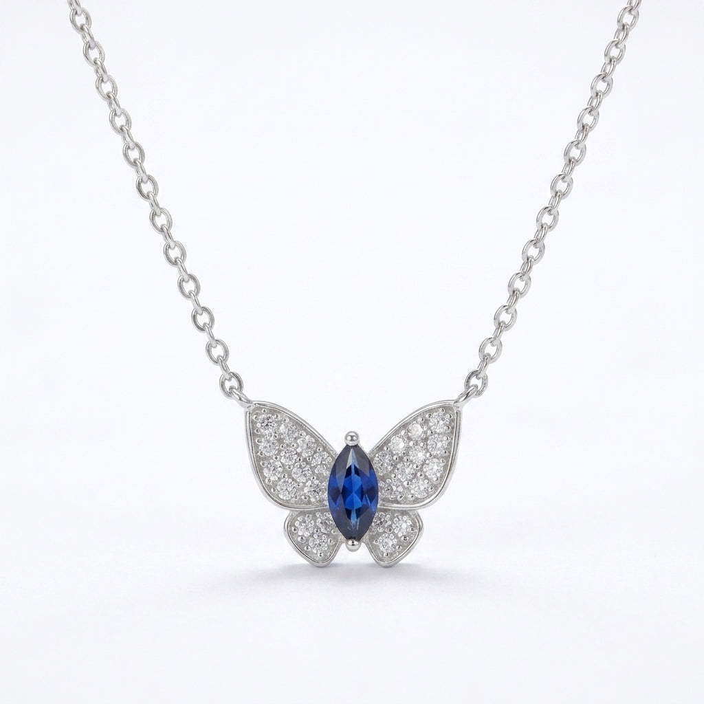 White background front view of a 925 sterling silver marquise sapphire butterfly necklace on a fine cable chain.