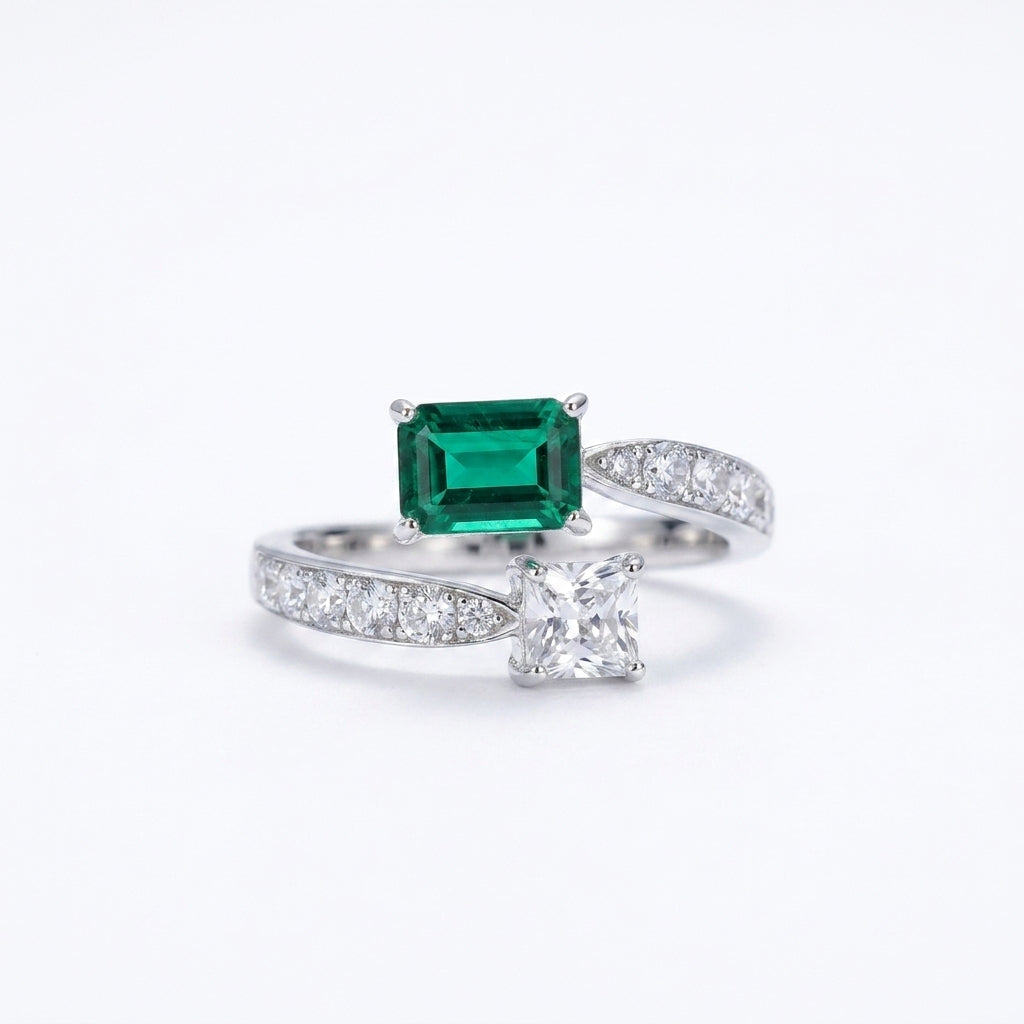 White background front view of a 925 sterling silver two-gemstone ring featuring a step-cut lab emerald and a square diamond.