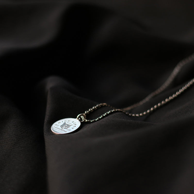 “Sterling silver minimalist cat tag necklace flat lay”